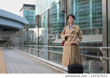 一位女商人正在商業區的人行道上等人。 一位女商人正在商業區的人行道上等人。 142327613