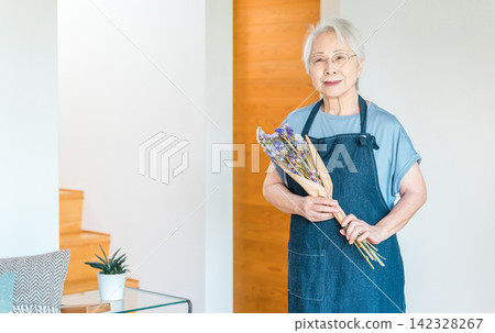 一位手捧乾花的老婦人，她以製作乾燥花為愛好。 142328267