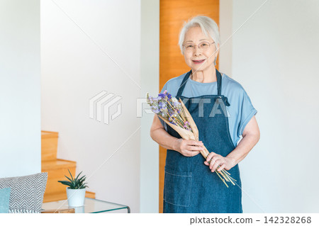 一位手捧乾花的老婦人，她以製作乾燥花為愛好。 142328268