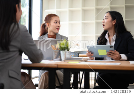 Business meeting with women discussing strategy using tablet and reports in office Business meeting with women discussing strategy using tablet and reports in office 142328339