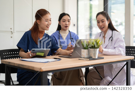 Healthcare team discussing patient care using laptop and tablet in modern office Healthcare team discussing patient care using laptop and tablet in modern office 142328350