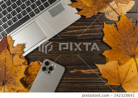 Smartphone and laptop with autumn leaves on a wooden desk Smartphone and laptop with autumn leaves on a wooden desk 142328691