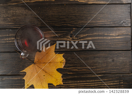 Cozy mug of tea next to autumn leaves on a wooden table Cozy mug of tea next to autumn leaves on a wooden table 142328839