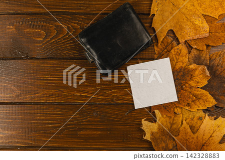 Leaves and blank card on wooden table in autumn setting Leaves and blank card on wooden table in autumn setting 142328883