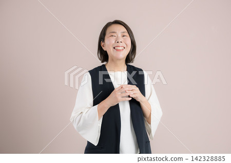 A portrait of a woman in her 40s expressing joy and gratitude with a smile and a "thank you" pose against a pink background, celebrating the achievement of her goal. A portrait of a woman in her 40s expressing joy and gratitude with a smile and a "thank you" pose against a pink background, celebrating the achievement of her goal. 142328885