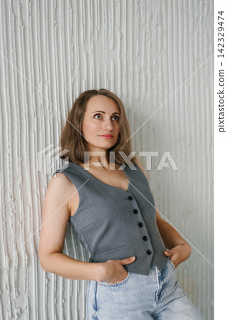 Stylish Female Model in Grey Vest Leaning Against Wall Stylish Female Model in Grey Vest Leaning Against Wall 142329474