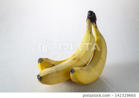 A product photo of fresh fruit: yellow bananas arranged against a white background. A product photo of fresh fruit: yellow bananas arranged against a white background. 142329668