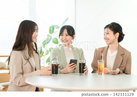 Three working women sharing information while looking at their smartphones, businesswomen 142331129