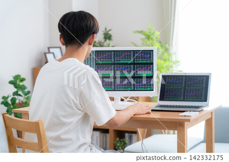 一位年輕人在家投資股票。 142332175