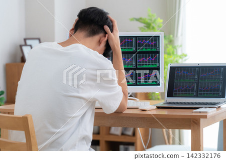 一位年輕人在家投資股票。 142332176