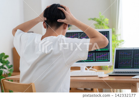 一位年輕人在家投資股票。 142332177