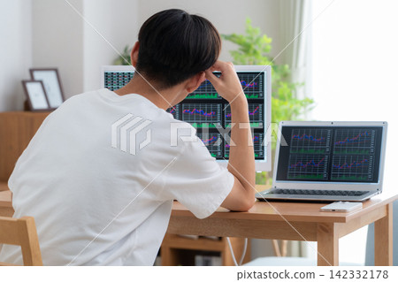 一位年輕人在家投資股票。 142332178