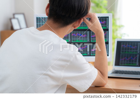 一位年輕人在家投資股票。 142332179