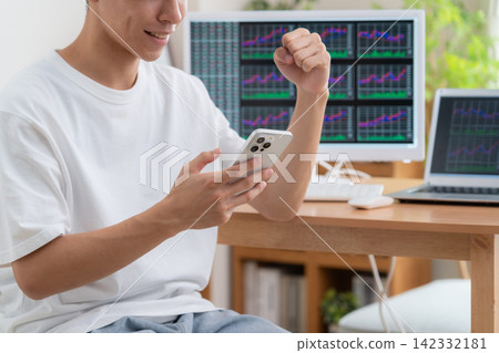 一位年輕人在家投資股票。 142332181