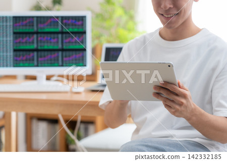 一位年輕人在家投資股票。 142332185