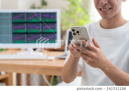 A young man invests in stocks from home. A young man invests in stocks from home. 142332186