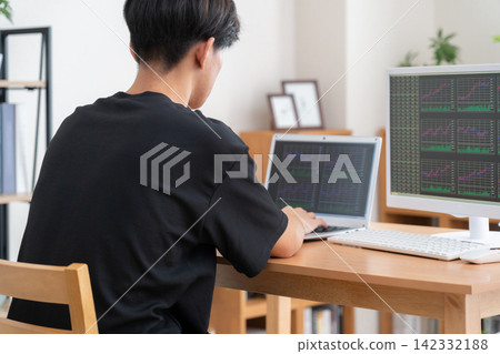 一位年輕人在家投資股票。 142332188
