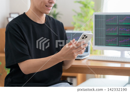 A young man invests in stocks from home. A young man invests in stocks from home. 142332190