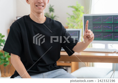 A young man invests in stocks from home. A young man invests in stocks from home. 142332196