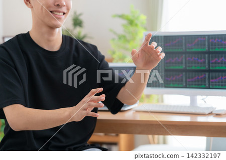 A young man invests in stocks from home. 142332197