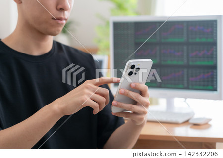 A young man invests in stocks from home. A young man invests in stocks from home. 142332206