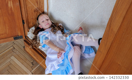 Little girl lying inside wardrobe smiling in blue frilled dress and white stockings, curled on wooden parquet near framed pictures, soft window light, playful cozy mood, vintage cabinet setting, Little girl lying inside wardrobe smiling in blue frilled dress and white stockings, curled on wooden parquet near framed pictures, soft window light, playful cozy mood, vintage cabinet setting, 142332330