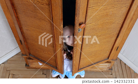 Child peeking from wardrobe door, curious preschooler playing hideandseek in cozy bedroom, wooden wardrobe panels and parquet floor visible, shy smile and bright eyes, hands gripping door edge, soft Child peeking from wardrobe door, curious preschooler playing hideandseek in cozy bedroom, wooden wardrobe panels and parquet floor visible, shy smile and bright eyes, hands gripping door edge, soft 142332331
