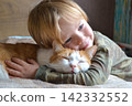 Portrait of happy adorablechild aged four years old on the bed in his room whit sleeping red cat. Thoughtful look. High quality photo 142332552