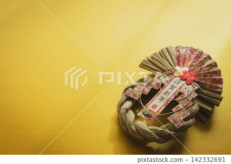新年裝飾品，以金色為背景，繫著一條寫有「新年快樂」字樣的注連繩。 142332691