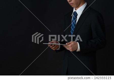 年輕的商人，背景是黑色的。 142333115