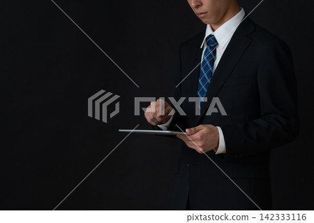 年輕的商人，背景是黑色的。 142333116