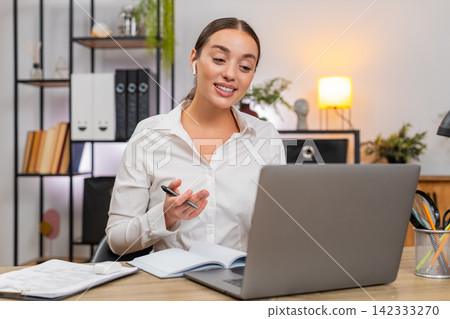 Young businesswoman on laptop video call greets nods takes notes and sets clear deadlines with team 142333270