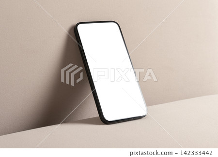 Smartphone with blank screen on beige surface. Minimal mobile mockup with copy space and clean studio lighting. Ideal for app advertising and branding.. Smartphone with blank screen on beige surface. Minimal mobile mockup with copy space and clean studio lighting. Ideal for app advertising and branding.. 142333442