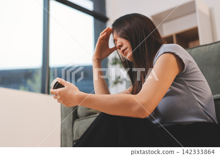 Young Asian woman sitting in bed and holding her head in pain with headache, feeling depressed and suffering 142333864
