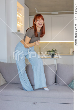 Young woman dances and jumps to loud music playful party mood carefree joy weekend vacation freedom Young woman dances and jumps to loud music playful party mood carefree joy weekend vacation freedom 142334226