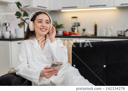 Young woman in wireless headphones listens to music with smartphone relax closed eyes chill zen mood Young woman in wireless headphones listens to music with smartphone relax closed eyes chill zen mood 142334276