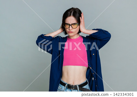 Woman covering ears with hands turning head away indicating unwillingness to hear refuse gesture Woman covering ears with hands turning head away indicating unwillingness to hear refuse gesture 142334301