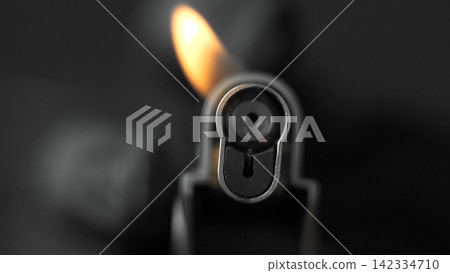 Lighter showing a small, vibrant flame burning against a dark, contrasting background, capturing heat and light Lighter showing a small, vibrant flame burning against a dark, contrasting background, capturing heat and light 142334710