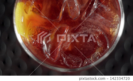 Negroni cocktail with ice cubes and orange peel close-up, enjoying refreshing aperitif drink 142334720