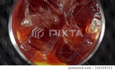 Cold refreshing dark beverage with ice cubes and lemon slice in a glass, top view, bubbles creating a refreshing texture Cold refreshing dark beverage with ice cubes and lemon slice in a glass, top view, bubbles creating a refreshing texture 142334721