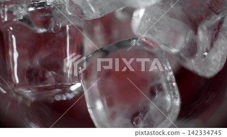 Ice cubes melting in a refreshing red drink, creating bubbles and a cooling liquid effect, close-up macro view Ice cubes melting in a refreshing red drink, creating bubbles and a cooling liquid effect, close-up macro view 142334745
