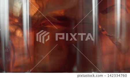 Brown liquid and ice in a glass, creating abstract patterns of light and dark, representing refreshment and chilled drinks Brown liquid and ice in a glass, creating abstract patterns of light and dark, representing refreshment and chilled drinks 142334760