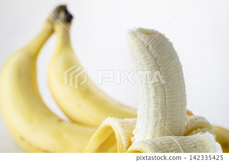 Peeled bananas and bunches of bananas, fresh fruit against a white background. Peeled bananas and bunches of bananas, fresh fruit against a white background. 142335425
