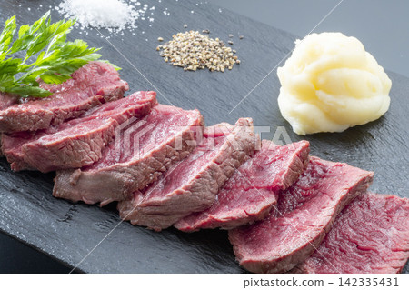 Slices of lean steak and side dishes served on a slate plate Slices of lean steak and side dishes served on a slate plate 142335431