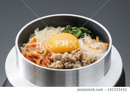 韓式拌飯(Bibimbap)是一種用鍋子烹調的韓國料理,盛在碗裡,上面放著一個雞蛋、肉末和蔬菜。 韓式拌飯(Bibimbap)是一種用鍋子烹調的韓國料理,盛在碗裡,上面放著一個雞蛋、肉末和蔬菜。 142335432