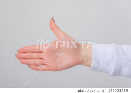 Person's hand extending, fingers together and thumb up, creating a playful gesture resembling a hand pistol, symbolizing communication, game, or direction Person's hand extending, fingers together and thumb up, creating a playful gesture resembling a hand pistol, symbolizing communication, game, or direction 142335489