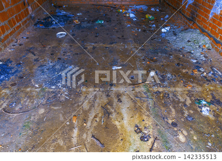 Empty brick garage floor littered with mud debris and discarded trash under dim daylight Empty brick garage floor littered with mud debris and discarded trash under dim daylight 142335513