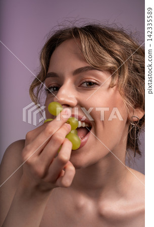 Young woman eating green grapes, expressing joy and healthy living. Focused on natural beauty, nutrition, and well-being Young woman eating green grapes, expressing joy and healthy living. Focused on natural beauty, nutrition, and well-being 142335589