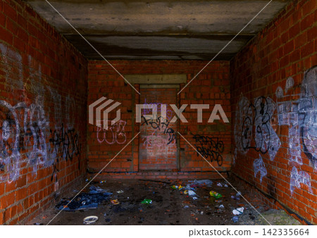 Abandoned brick shelter interior with colorful graffiti, damp concrete floor, and litter Abandoned brick shelter interior with colorful graffiti, damp concrete floor, and litter 142335664