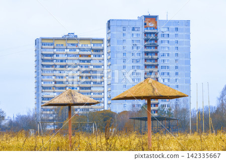 Rusty metal parasols in overgrown playground with Soviet-era apartment blocks in background Rusty metal parasols in overgrown playground with Soviet-era apartment blocks in background 142335667